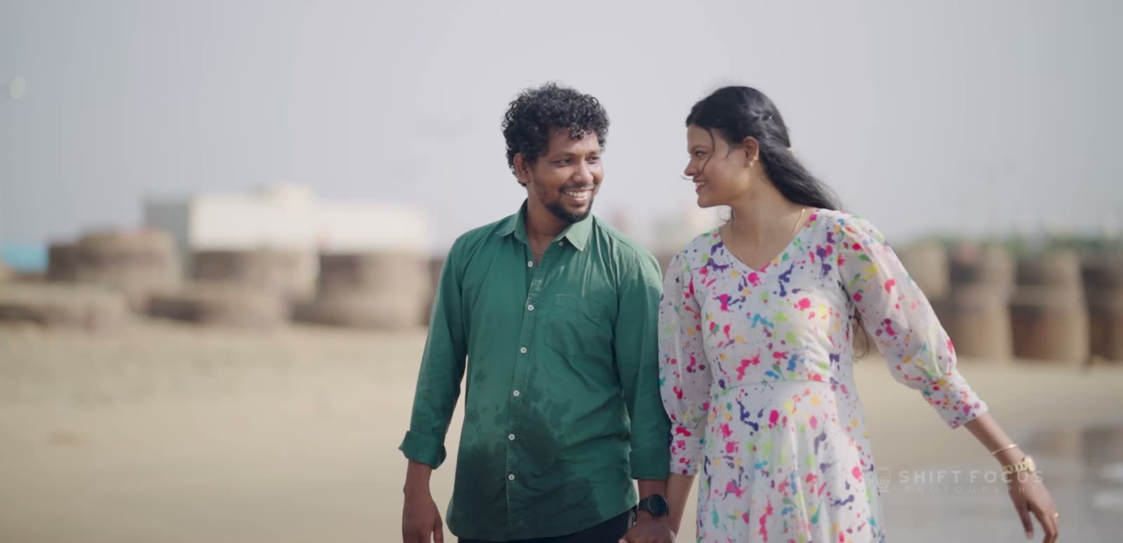 Naveen and Laila walking hand in hand on the beach, still from their candid film