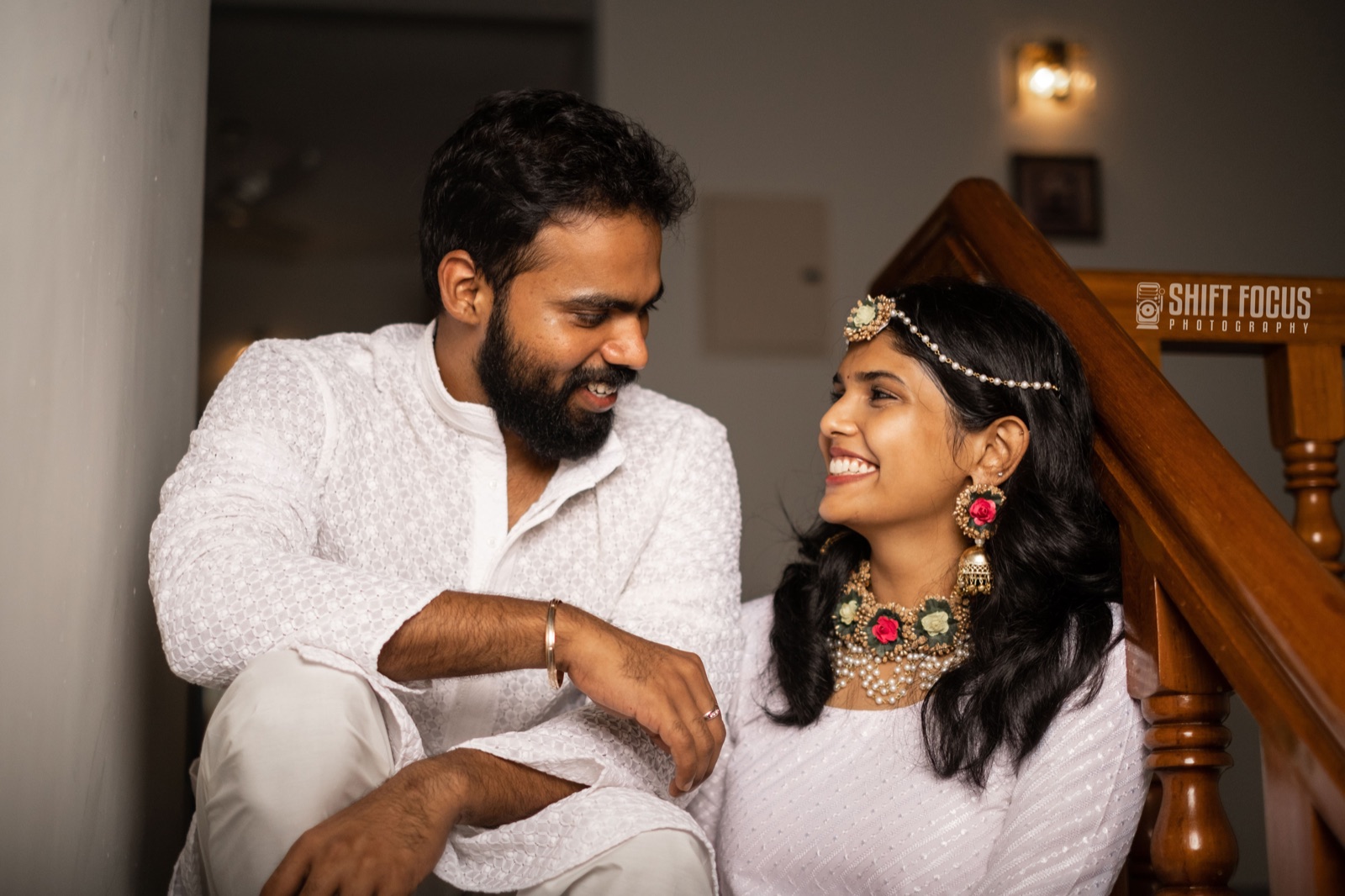 Couple in white sharing a laugh on the staircase